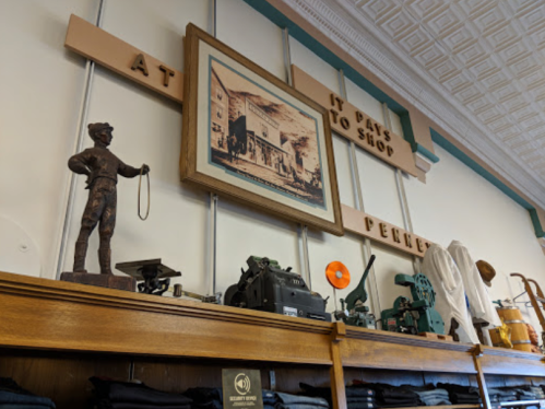 A vintage display featuring a statue, old photographs, and various antique tools on a wooden shelf.