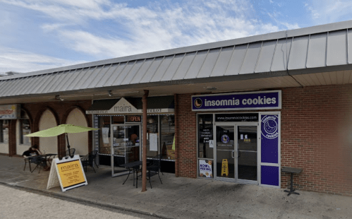 A storefront featuring "Insomnia Cookies" and "Maira" with outdoor seating and an open sign.