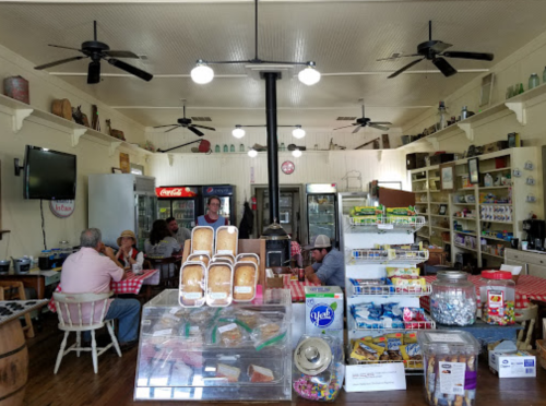 A cozy diner interior with checkered tables, a display of snacks, and patrons enjoying their meals.