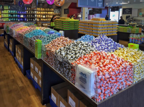A colorful display of assorted candies in a store, arranged in rows on tables with various packaging.