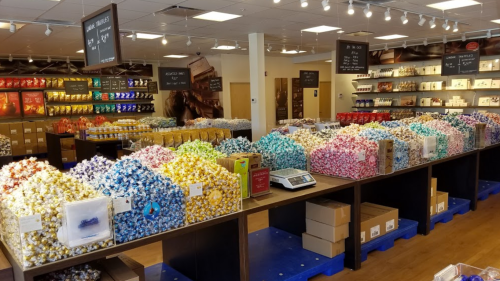 A colorful display of various candies and chocolates in a well-lit store, with shelves and tables filled with treats.