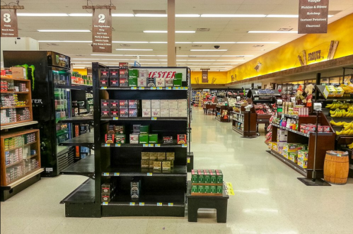 A grocery store aisle with shelves of products, including snacks and beverages, and a display labeled "TESTER."