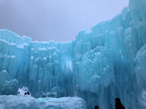 A stunning ice formation with towering blue icicles and a snowy ground, creating a magical winter atmosphere.