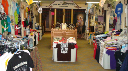 A colorful retail space filled with various T-shirts and merchandise, featuring a central display and decorative banners.