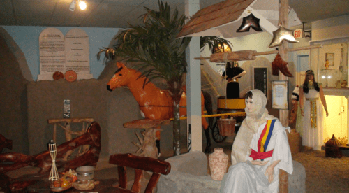 A museum display featuring a horse statue, a seated mannequin in traditional attire, and various artifacts.
