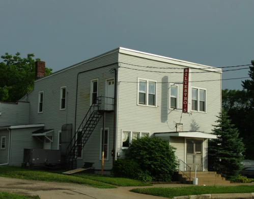 A two-story building with a sign reading "Stilestro's," featuring a staircase and greenery around it.