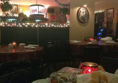 Cozy restaurant interior with dim lighting, tables set for dining, and a warm ambiance from candles and decorations.