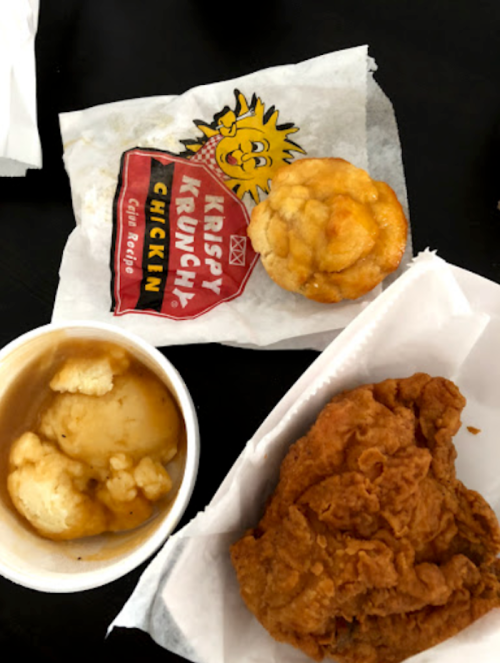 A plate featuring fried chicken, a biscuit, and a cup of mashed potatoes from Krispy Krunchy Chicken.