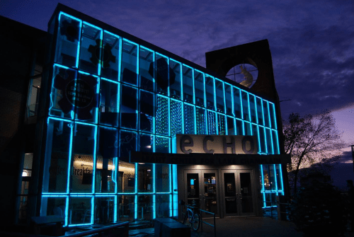 The ECHO Center illuminated with blue lights at dusk, showcasing modern architecture against a twilight sky.
