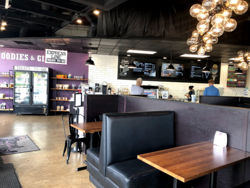 Interior of a casual eatery with booths, a counter, and menu displays, featuring modern lighting and a cozy atmosphere.