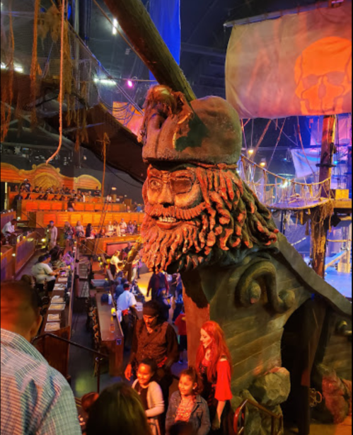 A large pirate statue with a detailed face and hat, set in a lively, colorful pirate-themed venue.
