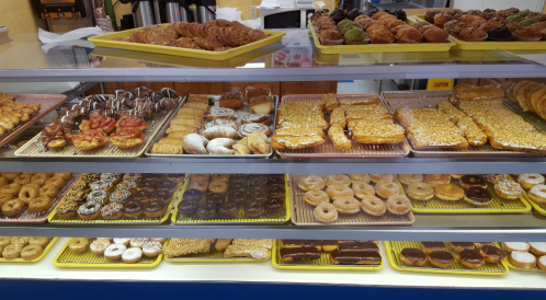 A display case filled with a variety of colorful pastries, donuts, and baked goods.