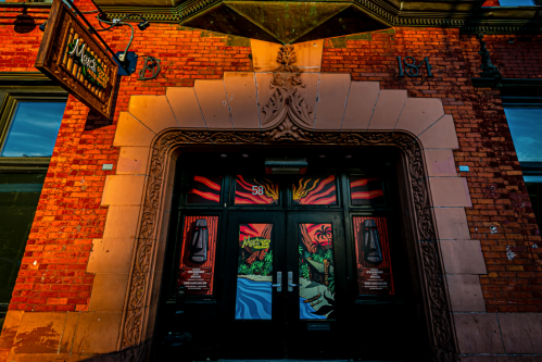 Colorful entrance of a brick building with decorative arch and vibrant artwork on the doors.