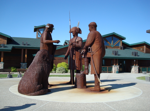A bronze sculpture depicting three figures and a bear, set in a plaza with a building in the background.