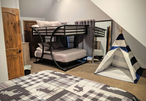 A cozy room featuring a bunk bed, a mirrored wardrobe, and a striped play tent on a carpeted floor.
