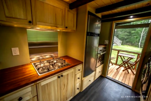 Cozy kitchen with wooden cabinets, a gas stove, and a view of an outdoor deck through a glass door.