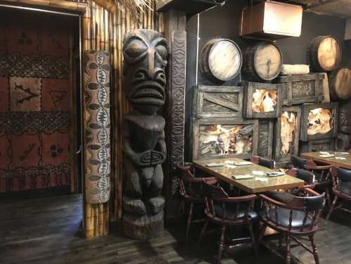 Interior of a themed restaurant featuring tribal decor, wooden carvings, and rustic tables and chairs.