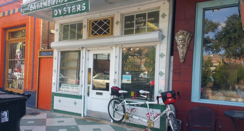 A restaurant entrance with a sign reading "Carmen's Oysters," featuring a bicycle parked outside.