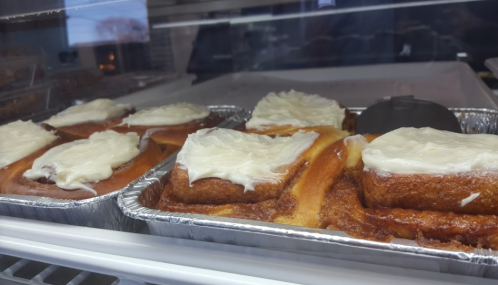 Freshly baked cinnamon rolls with cream cheese frosting in a display case.