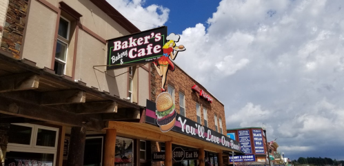 Sign for Baker's Cafe featuring a chef and a large burger, with a cloudy sky in the background.