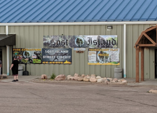 A building exterior featuring a large banner for "Lost Island" with park attractions and mini-golf information.