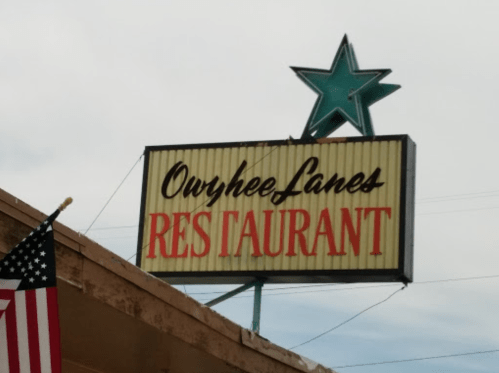 Sign for Owyhee Lanes Restaurant featuring a star and an American flag in the foreground.