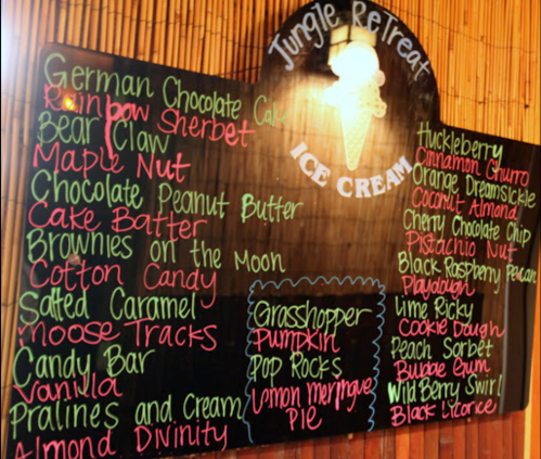 A chalkboard menu listing various ice cream flavors and desserts at Jungle Retreat, including cakes and sundaes.