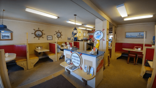Cozy restaurant interior with wooden booths, nautical decor, and a welcoming counter area.