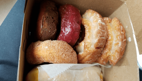 A box of assorted donuts, including chocolate, red velvet, glazed, and cinnamon sugar varieties.