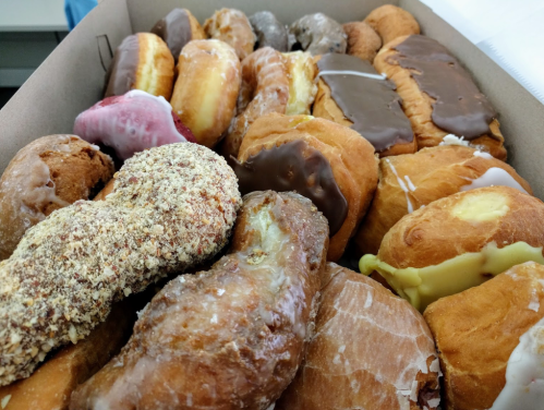 A box filled with a variety of colorful donuts, including glazed, chocolate-covered, and cream-filled options.