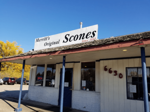 Exterior of Merritt's Original Scones, featuring a sign and a blue door, with cars parked outside.