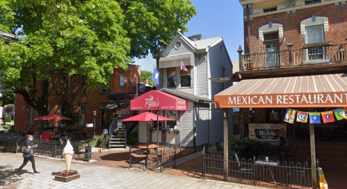 A sunny street scene featuring a Mexican restaurant and a small eatery with outdoor seating and colorful decorations.