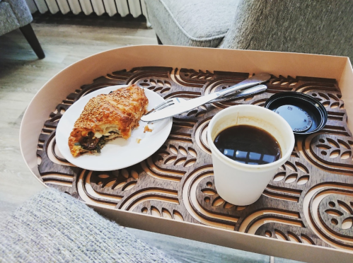 A cozy scene featuring a croissant on a plate and a cup of coffee on a decorative tray.