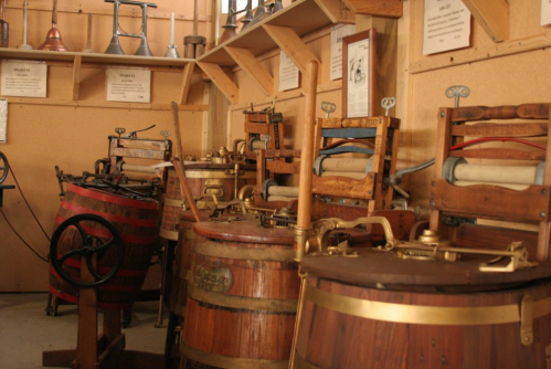 A collection of vintage wooden presses and barrels displayed in a museum setting.