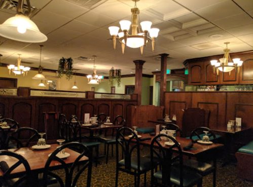 Cozy restaurant interior with wooden booths, tables, and warm lighting, creating an inviting atmosphere.