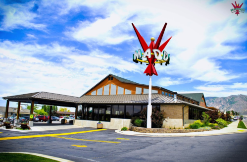 A colorful restaurant with a large sign reading "Mardi" and a scenic backdrop of mountains and blue skies.