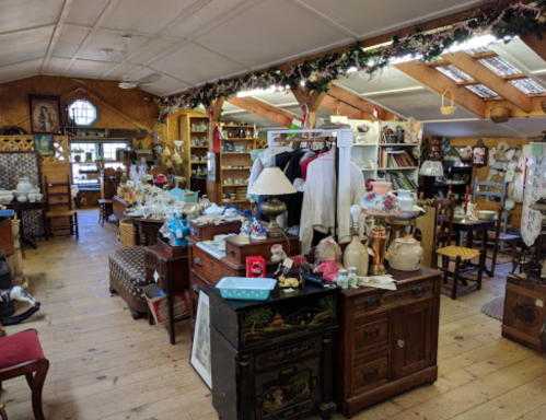 A cozy antique shop filled with various vintage items, furniture, and decor, creating a warm, inviting atmosphere.