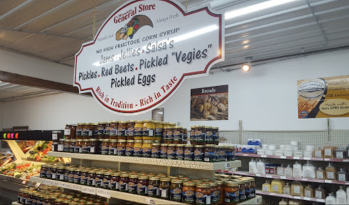 A general store interior featuring shelves of jars with various pickled products and a sign for "Jams, Jellies, Salsa."