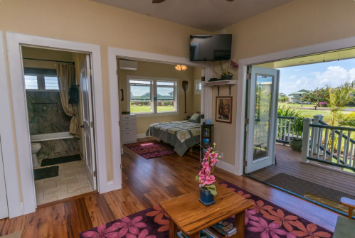 Cozy interior of a home featuring a living area, bedroom, and open doors leading to a porch with a view.