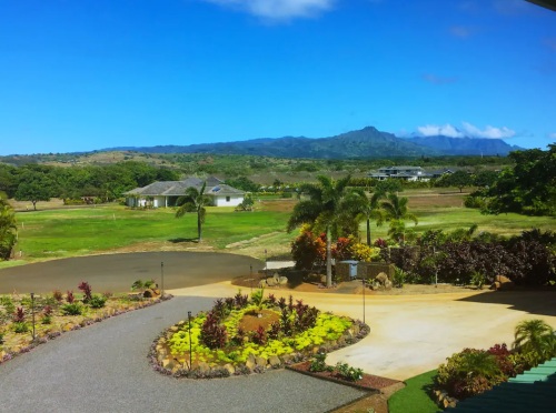 A scenic view of a lush landscape with mountains in the background, featuring a well-maintained garden and homes.