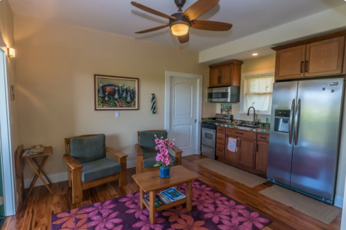 Cozy living space with two chairs, a coffee table, and a kitchen area featuring stainless steel appliances.