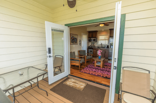 A cozy porch with a table and chairs, leading into a bright living area with a kitchen and colorful decor.