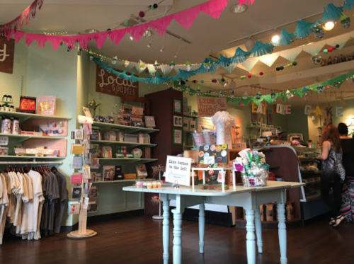 A colorful shop interior with shelves of goods, festive decorations, and a display table in the center.