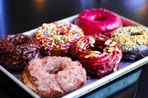 A tray of assorted donuts, including chocolate, glazed, and sprinkled varieties, with different toppings and flavors.