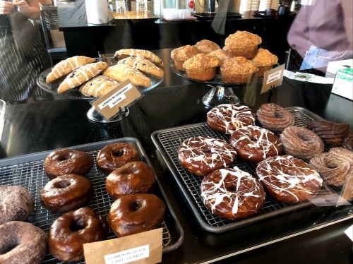 A display case filled with various baked goods, including donuts, muffins, and pastries.