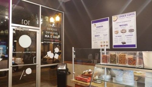 Interior of a dessert shop featuring a glass display case, menu board, and entrance with a modern design.