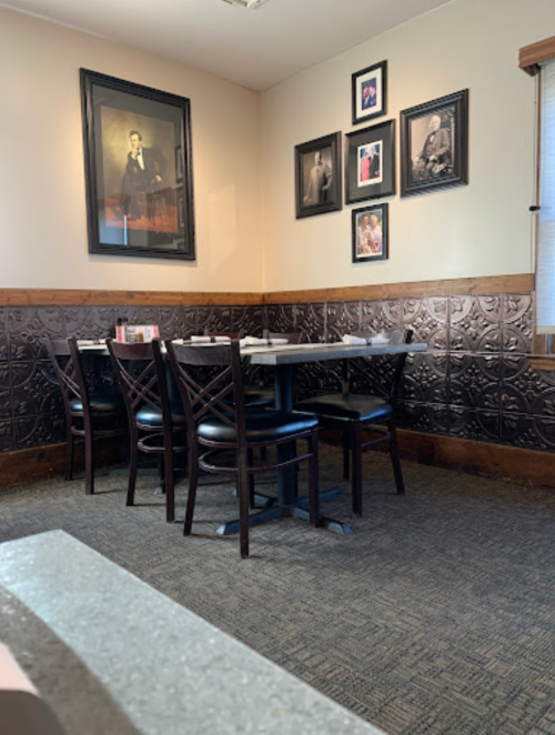 A cozy restaurant corner with a table and chairs, adorned with framed pictures on the wall.