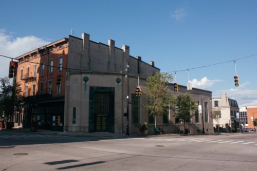A street corner featuring a mix of historic and modern buildings under a clear blue sky with traffic lights.