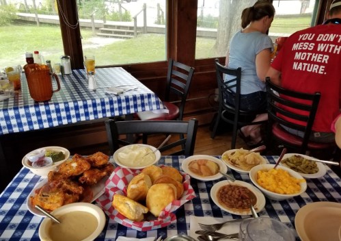 A table set with various dishes, including fried chicken, sides, and drinks, in a cozy dining area.