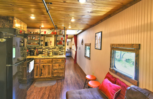 Cozy interior of a rustic kitchen and living area with wooden accents, a sofa, and bright decor.